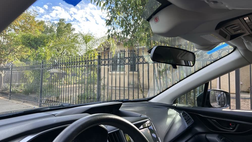 The rear-view mirror and forward-camera housing behind a newly fitted windshield